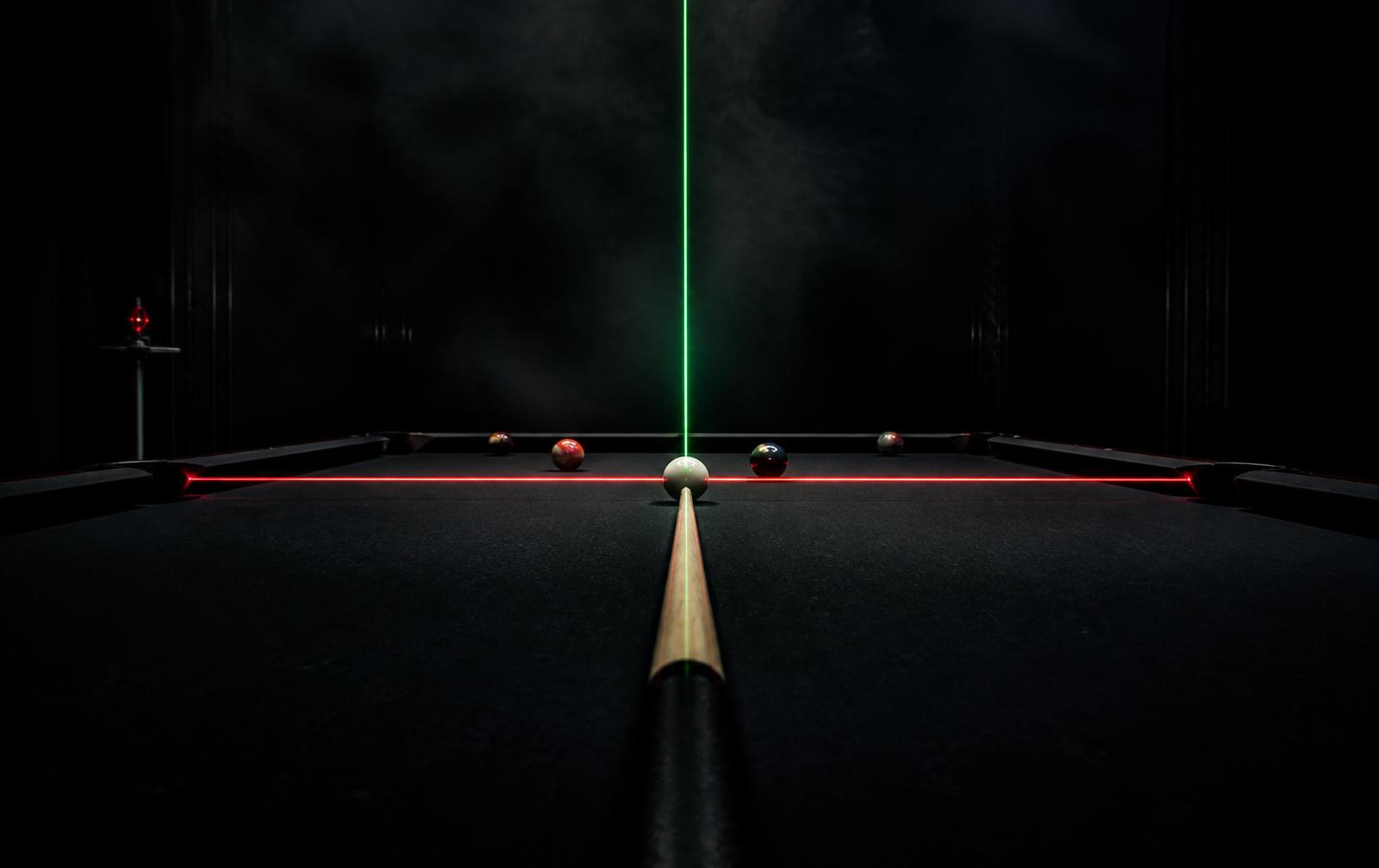 Red and green laser lines crossing over a cue ball on a dark billiards table